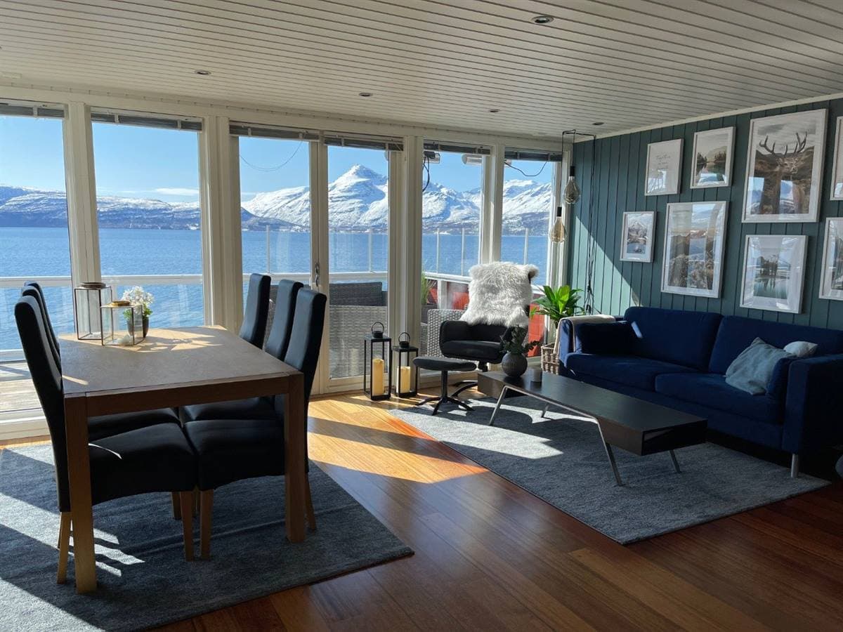Vardagsrum och matplats med utsikt över fjorden och fjällen