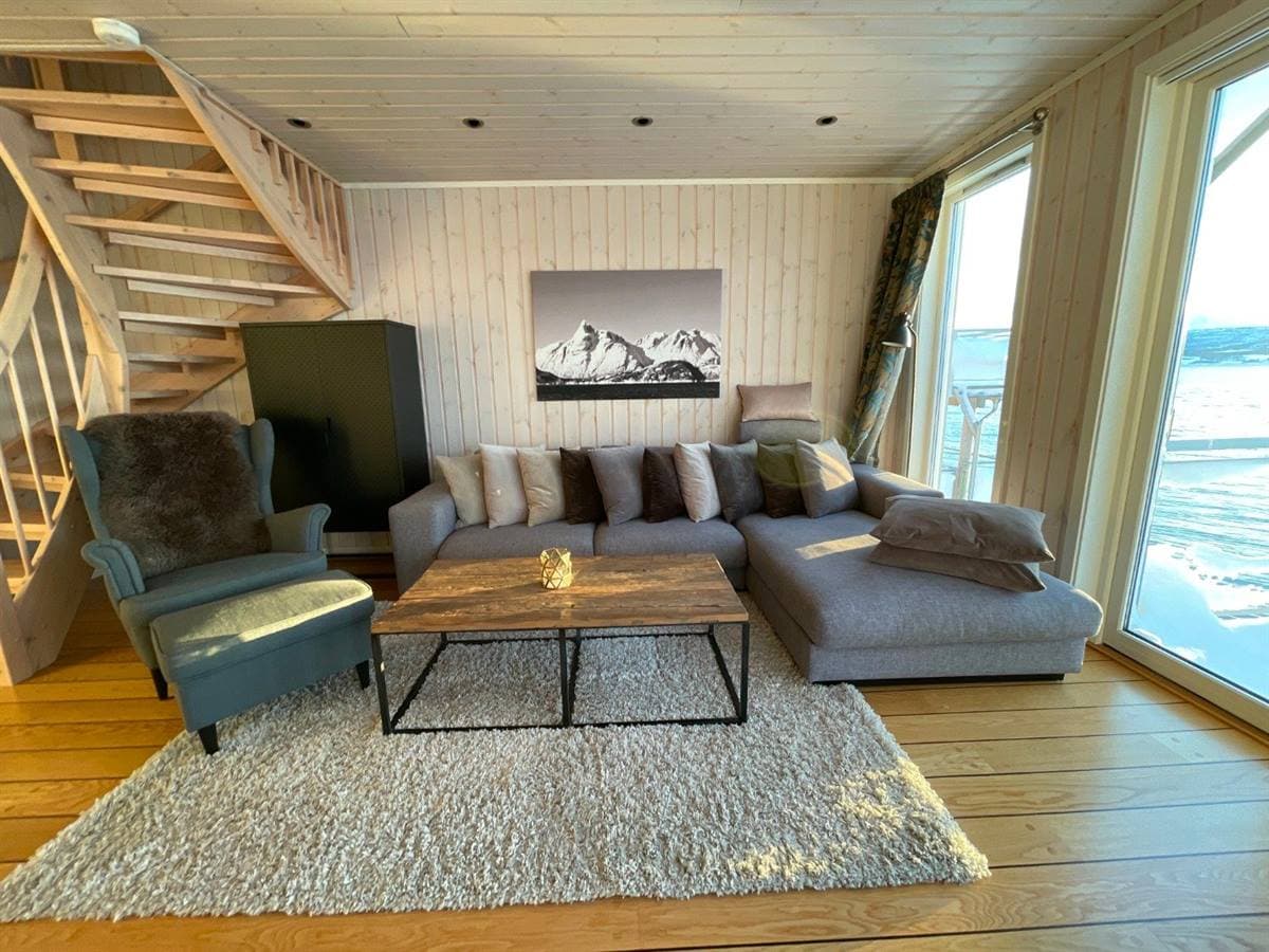 Vardagsrum med soffa, trappa och fjordutsikt