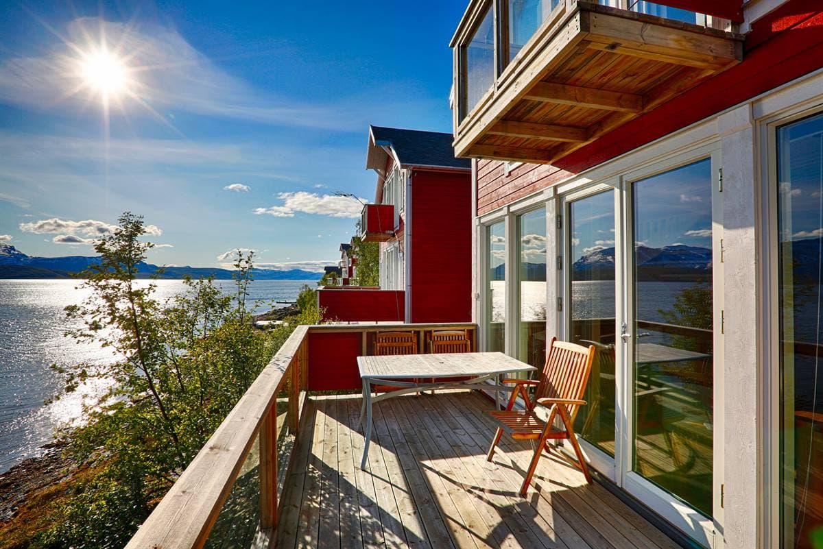Balkong med bord och stolar ovanför fjorden