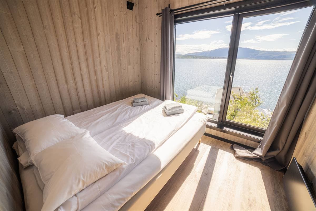 Sovrum med dubbelsäng och fönster mot fjorden