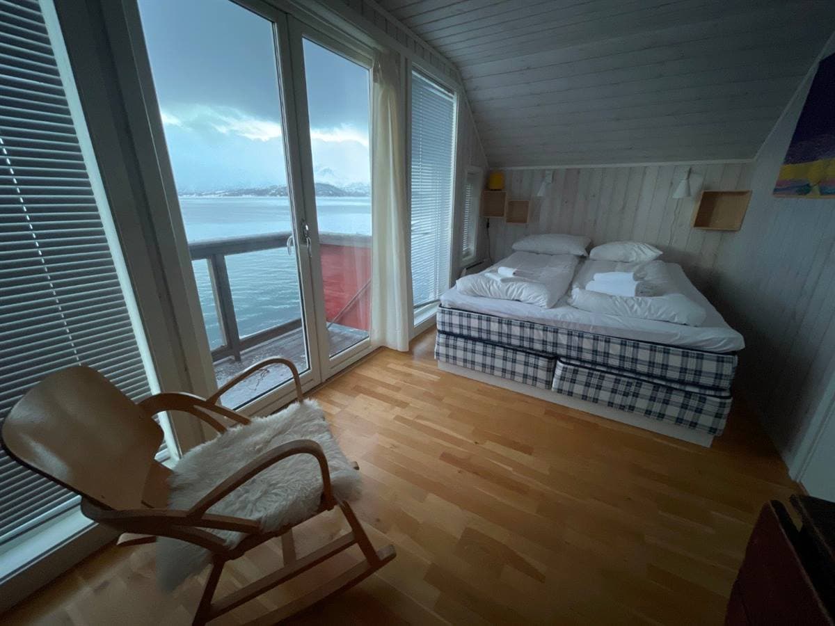 Sovrum med dubbelsäng, fönster mot fjorden och gungstol